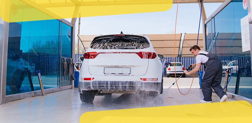 man washing a white car at self service car wash