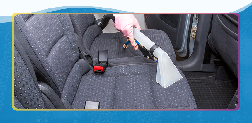 someone vacuuming car with handheld vacuum